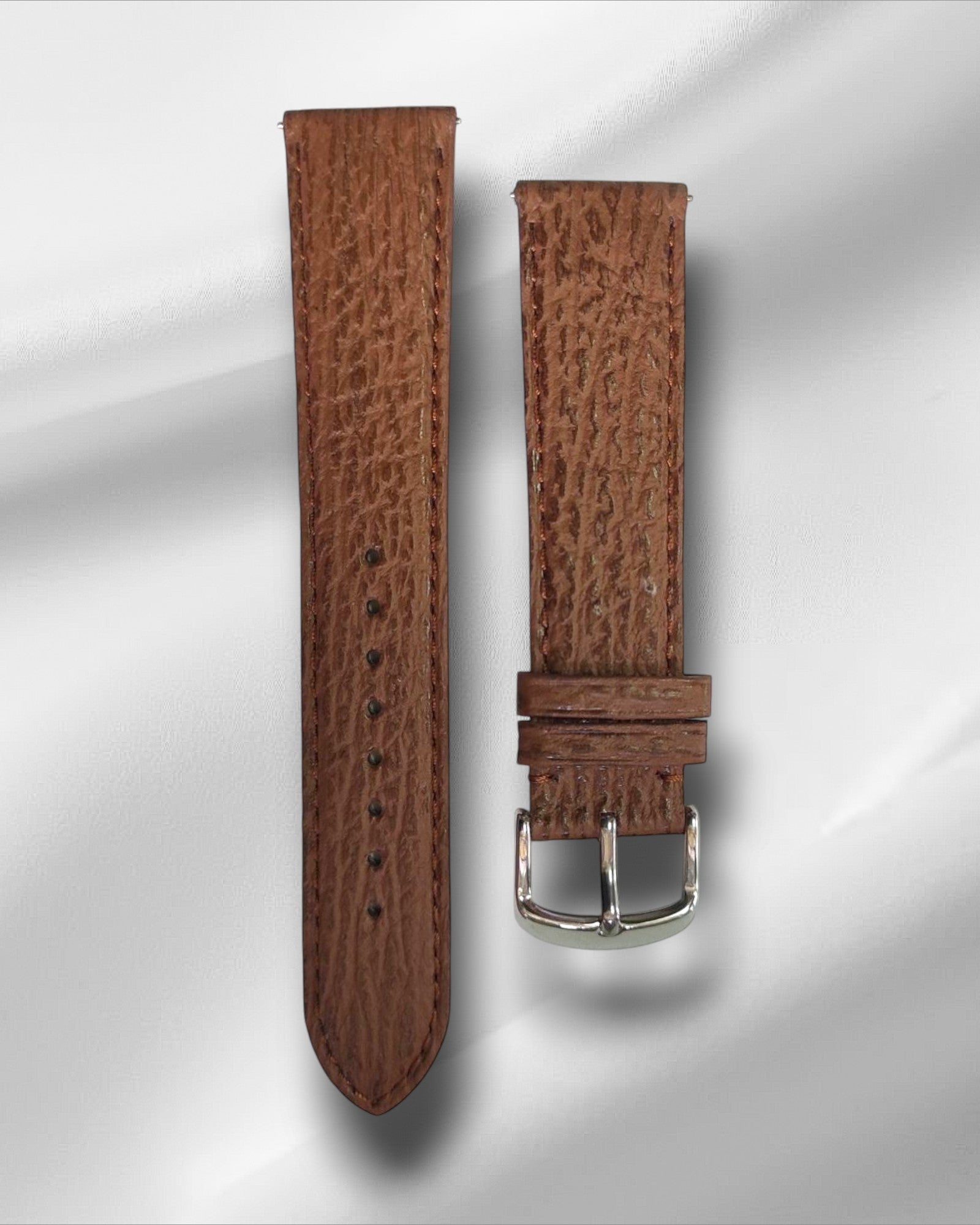 A brown sharkskin leather watch strap with a steel tang buckle and quick-release spring bars.