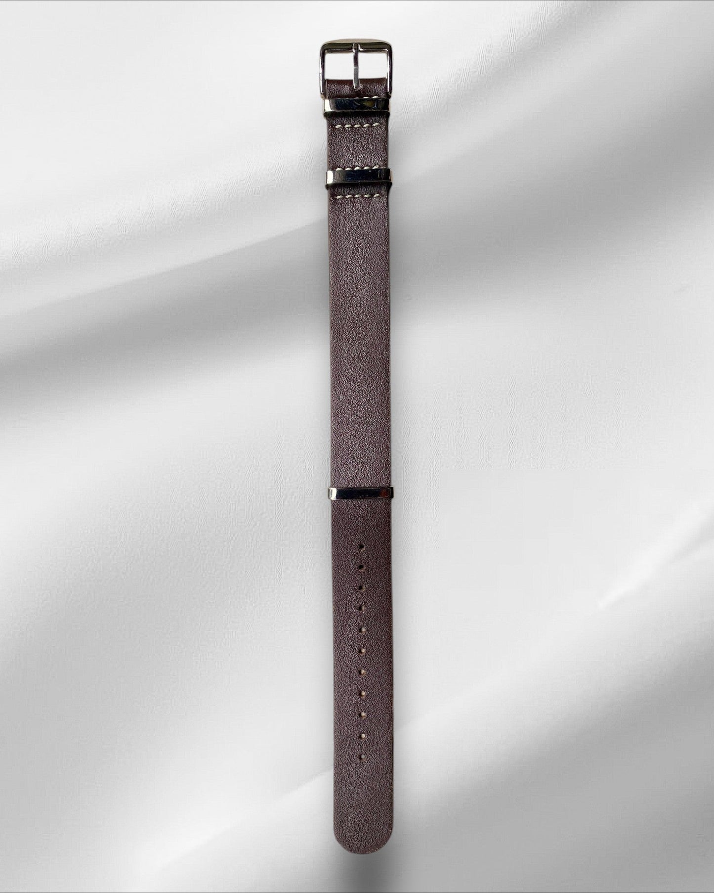 Brown watch strap with silver buckle on a white background