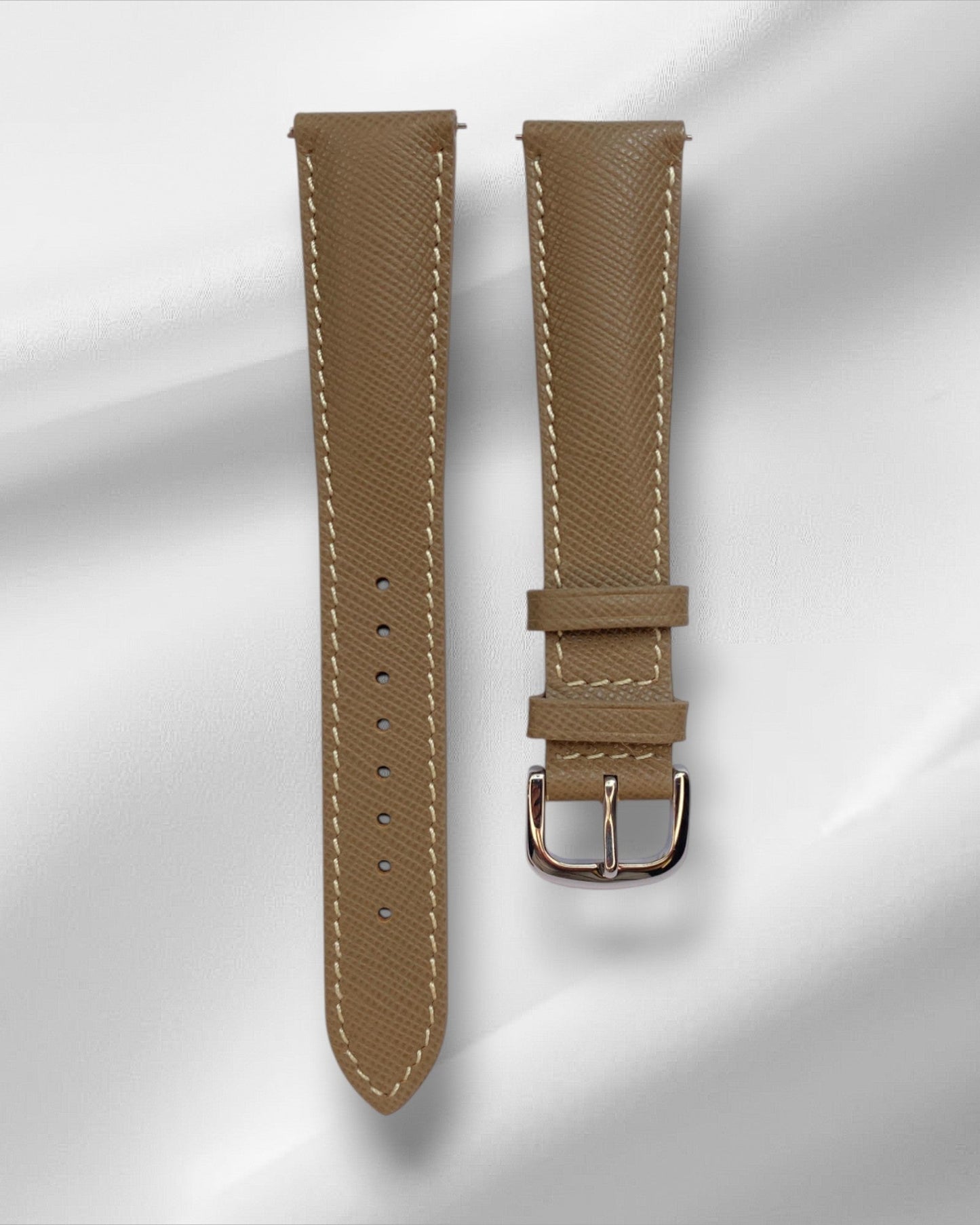 Taupe watch strap with silver buckle on a light gray background