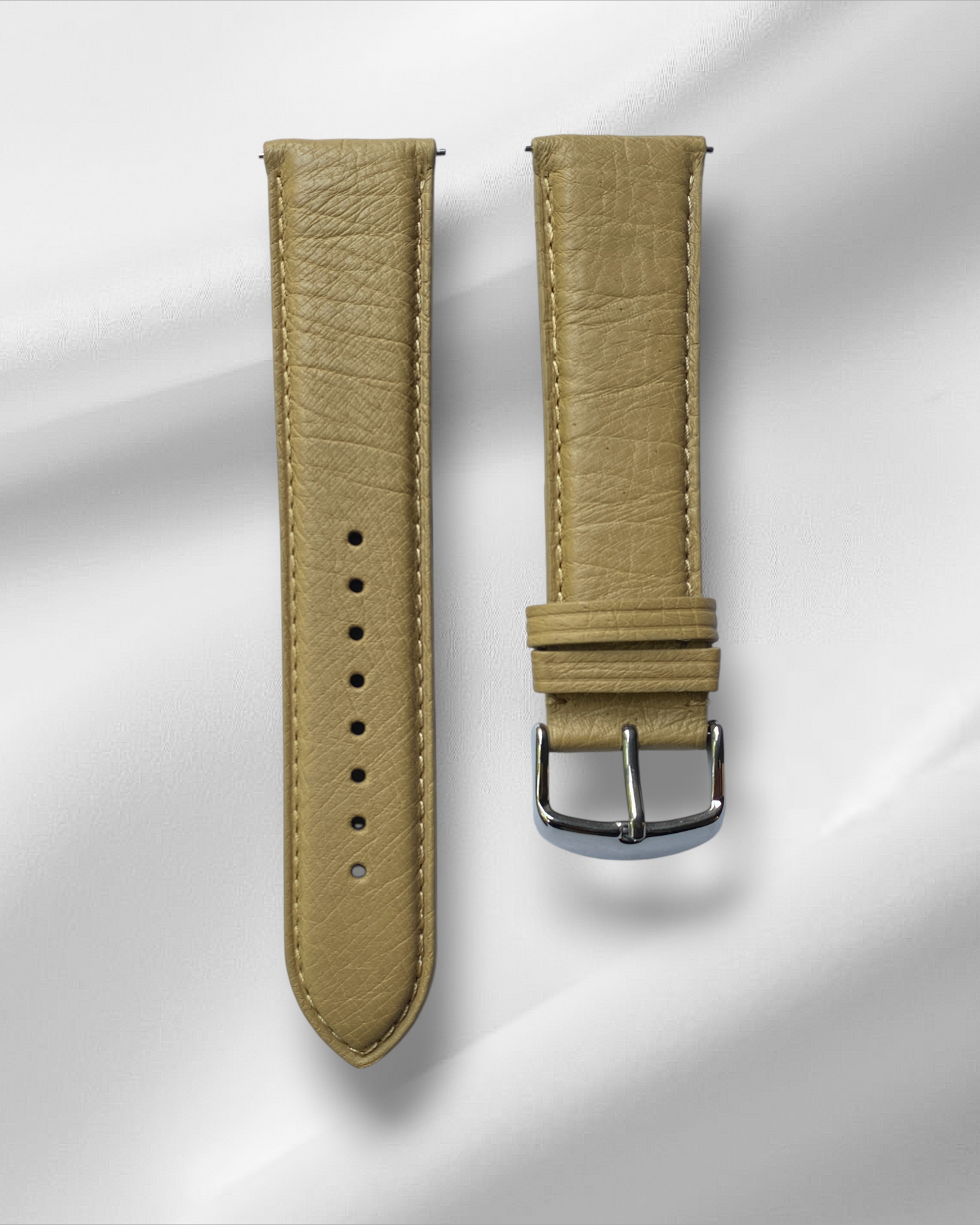 Beige leather watch strap with silver buckle on a light gray background