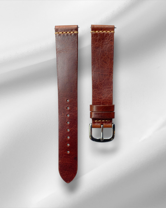 Brown leather watch strap with silver buckle on a light gray background