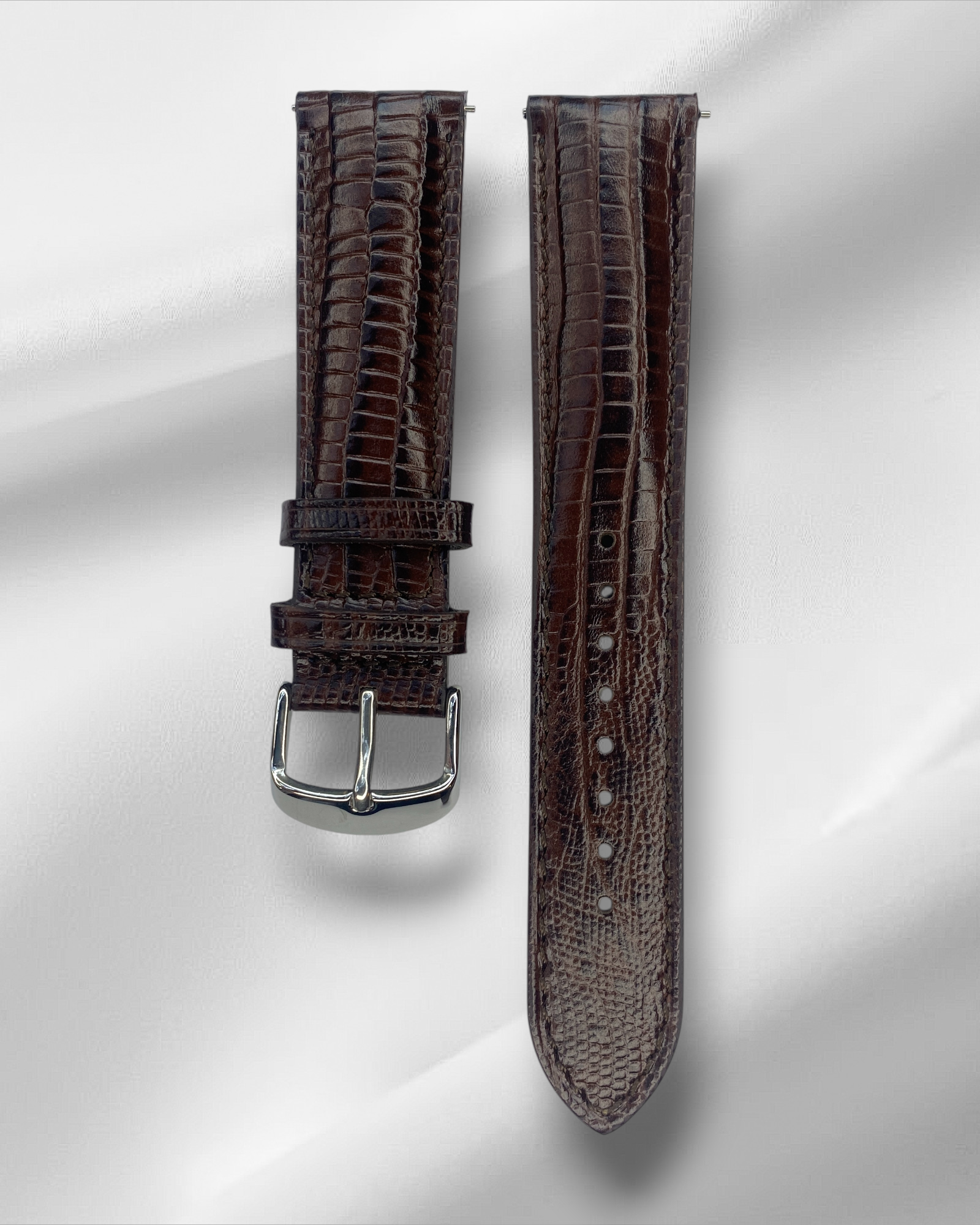 Brown textured watch strap with silver buckle on a light gray background