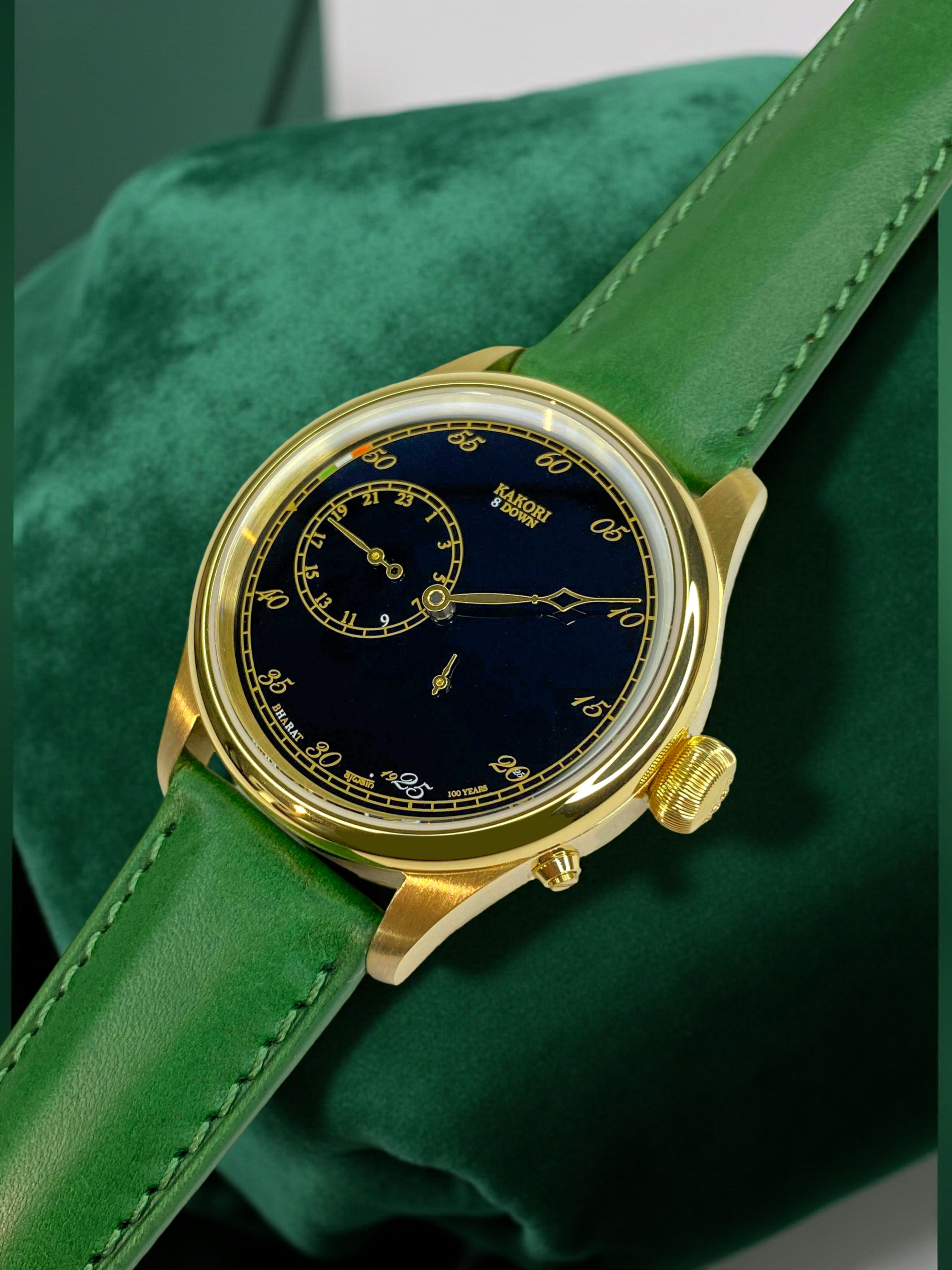 Gold wristwatch with a green leather strap on a green cushion