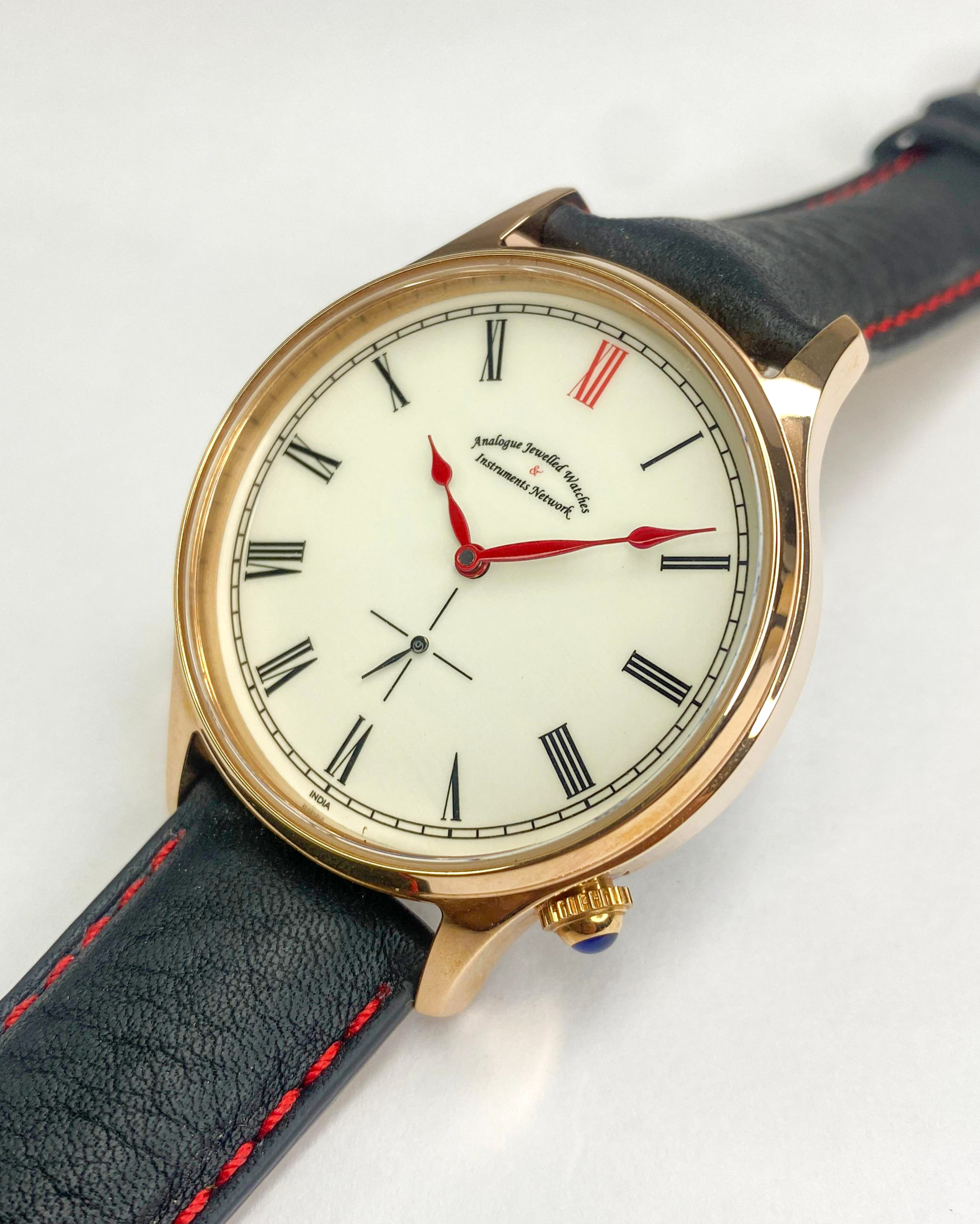 Wristwatch with rose gold case and black leather strap on a white background