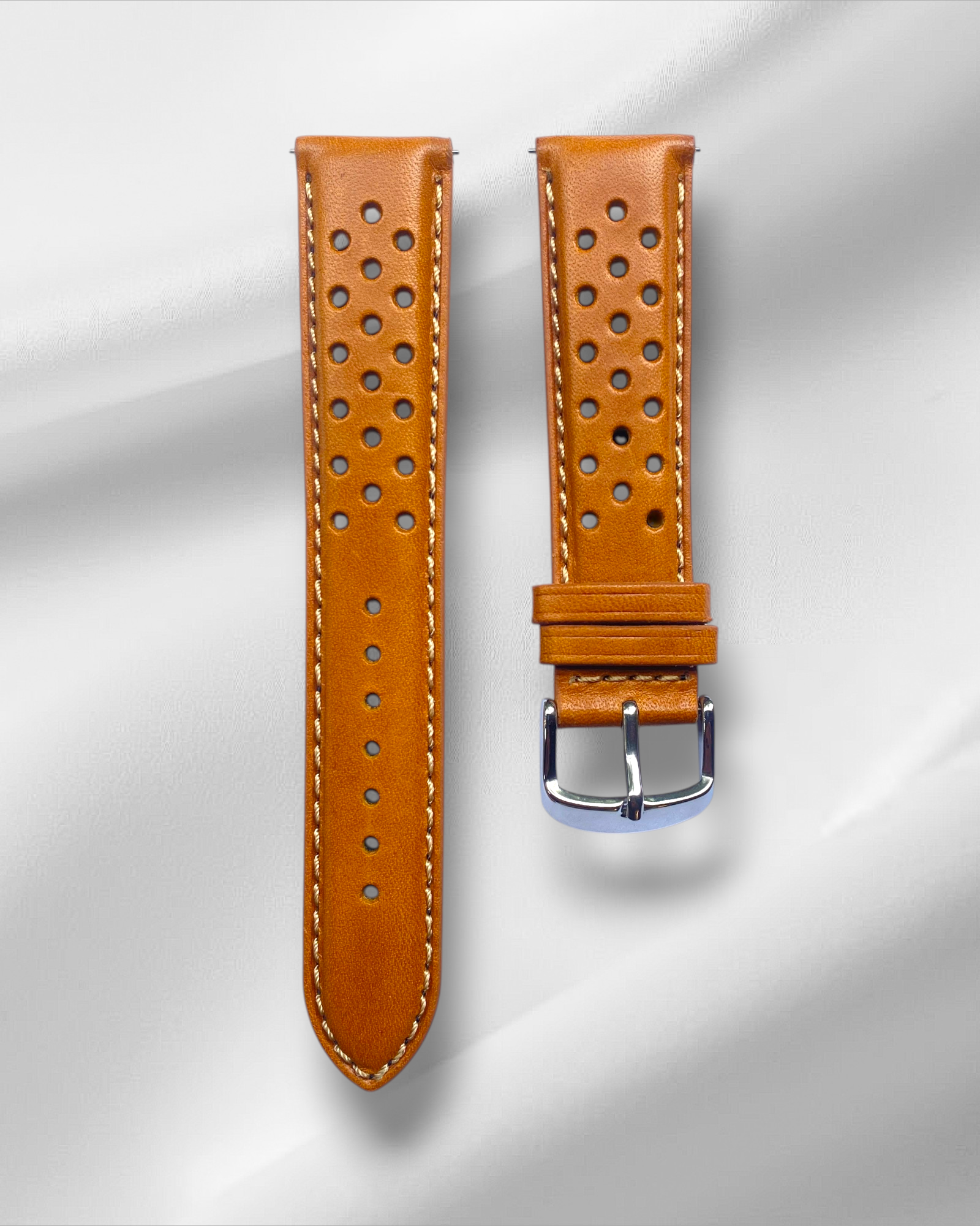Tan leather watch strap with silver buckle on a light gray background
