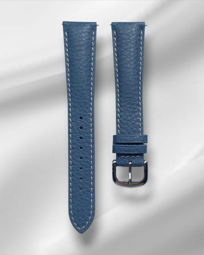 Blue watch strap with silver buckle on a light gray background