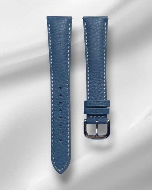 Blue watch strap with silver buckle on a light gray background