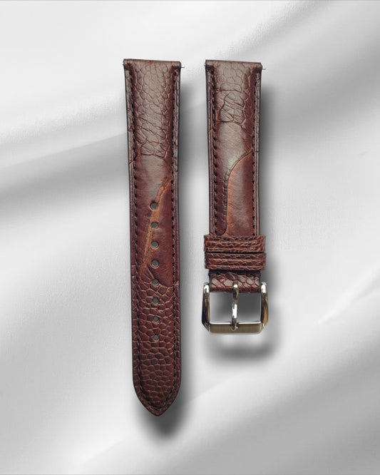 A two-tone brown ostrich leg leather watch strap with a steel tang buckle and quick release spring bars, displayed on a light background.