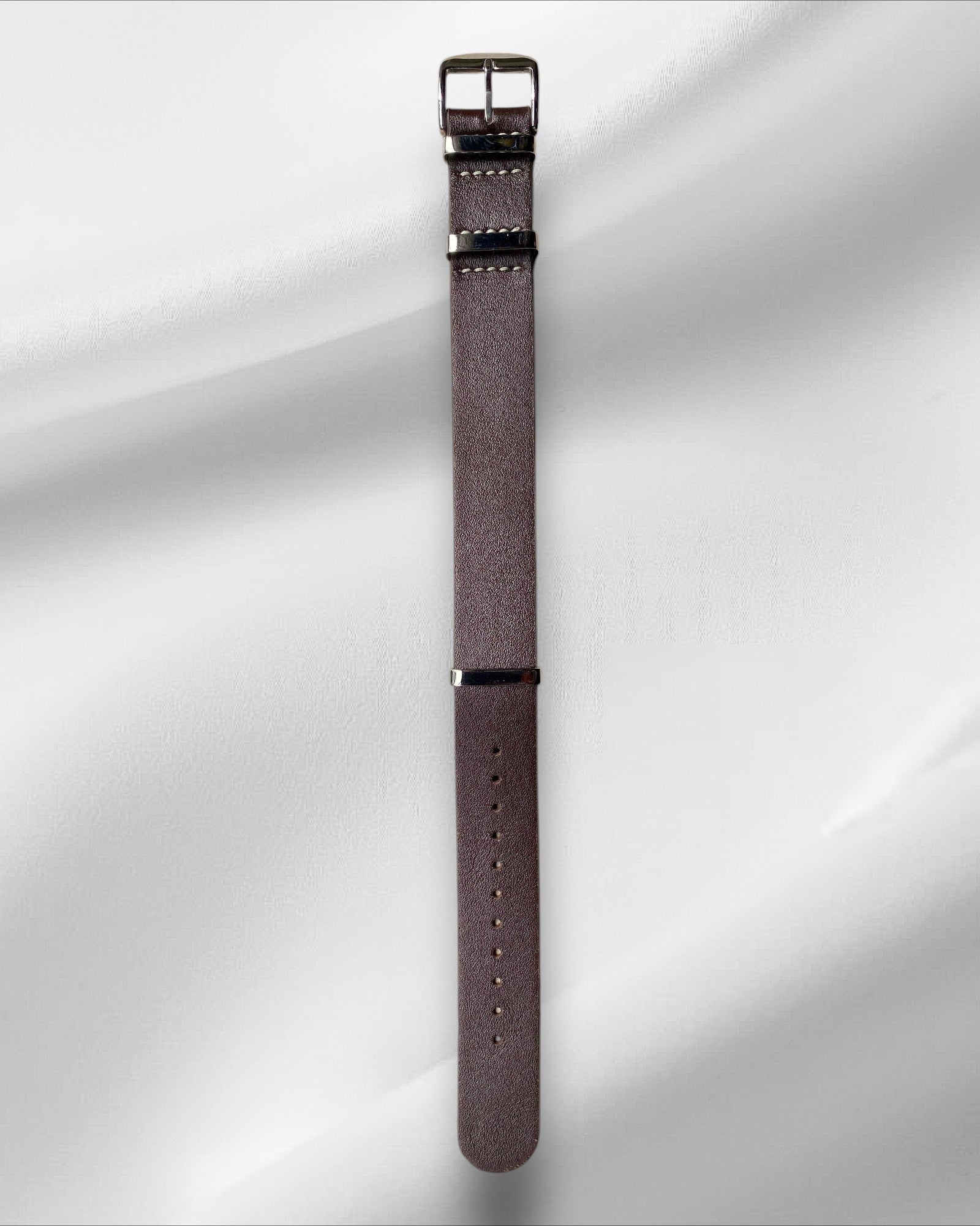 Brown watch strap with silver buckle on a white background
