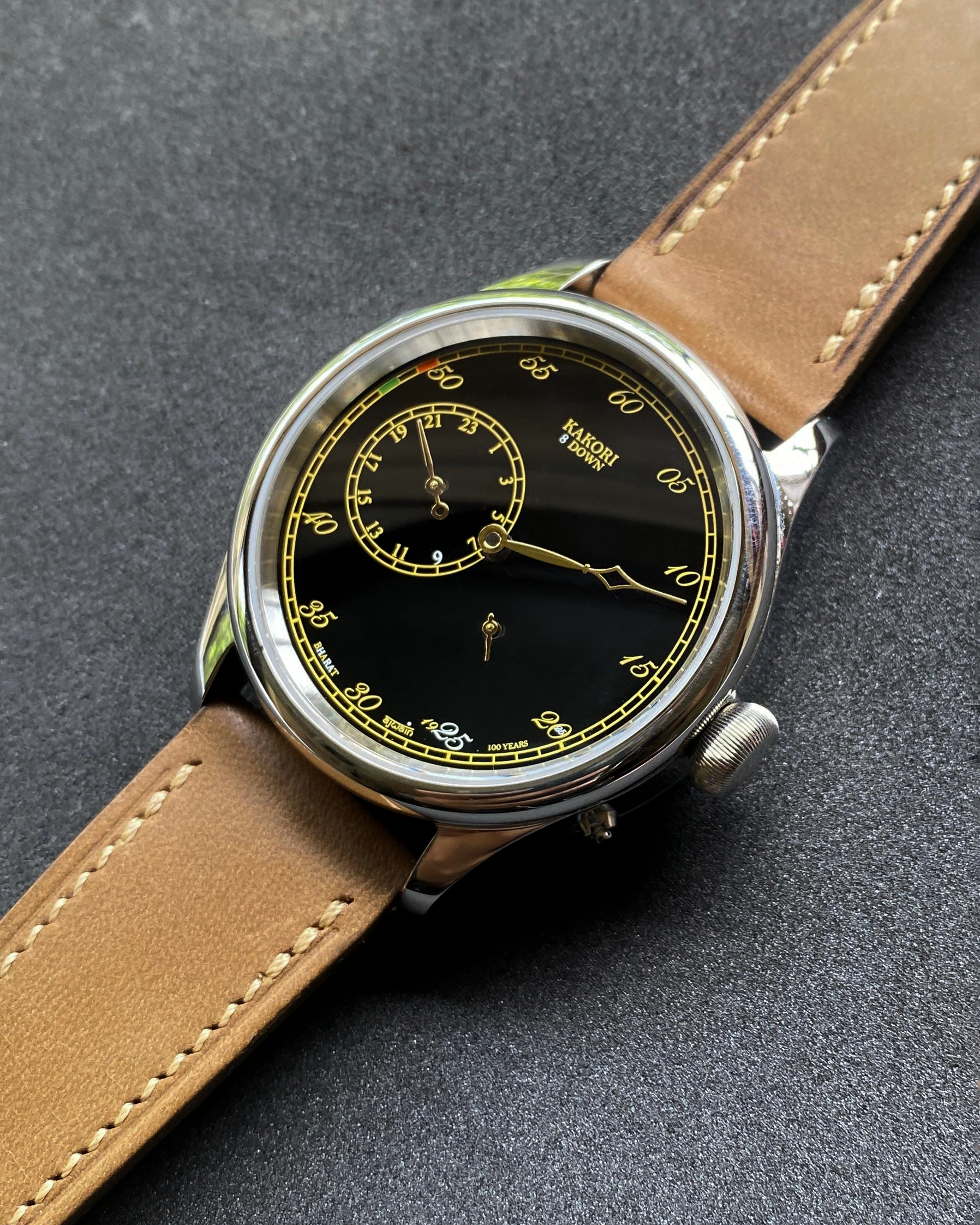 Wristwatch with brown leather strap and black dial on a dark gray background