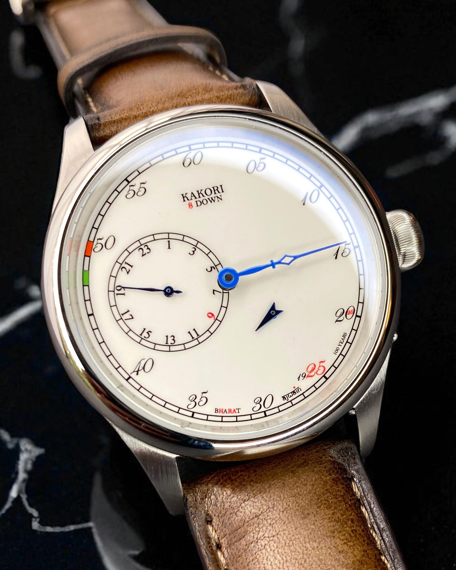 Vintage-style watch with brown leather strap on a dark marble background