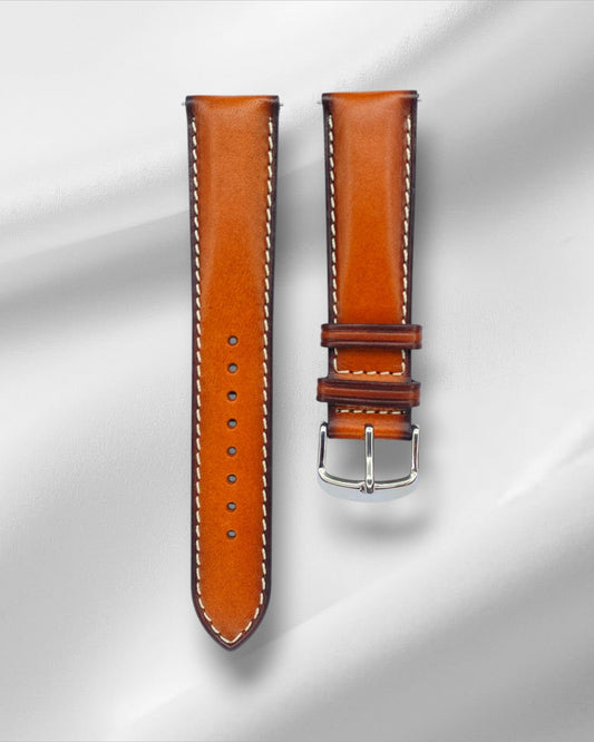 Brown leather watch strap with silver buckle on a light gray background